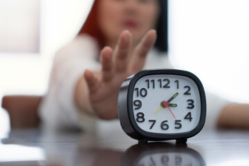 Cropped image of business woman with alarm clock working under deadline in office.