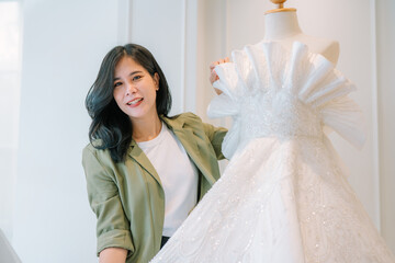 Attractive young bride is smiling while choosing wedding dress in modern wedding salon
