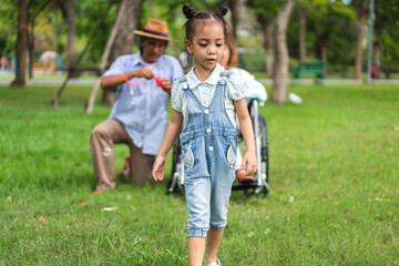 Obraz premium Portrait of happy love asian grandfather with grandmother and asian little cute girl enjoy relax in summer park.Young girl with their laughing grandparents smiling together.Family and togetherness