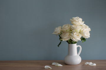 bouquet of white roses in jug in background blue wall
