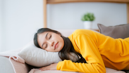 Asian woman resting at home on couch, feeling exhausted after work, lacking energy, or overworked, too tired, and lacking motivation