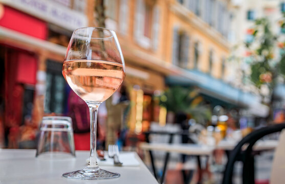 Fototapeta Glass of rose provencal wine at an outdoor restaurant with a background of blurred buildings in Old Town Vieille Ville in Nice, South of France