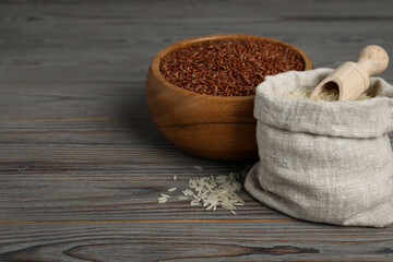 Bag and bowl with different sorts of rice on wooden table. Space for text