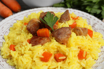 Delicious pilaf with meat and carrot on white plate, closeup
