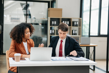 Businesswomen work and discuss their business plans. A Human employee explains and shows her colleague the results paper in modern office.