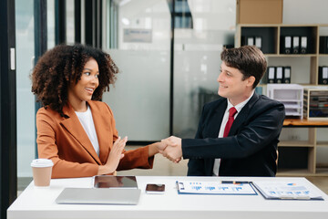 Businesswomen work and discuss their business plans. A Human employee explains and shows her colleague the results paper in modern office.