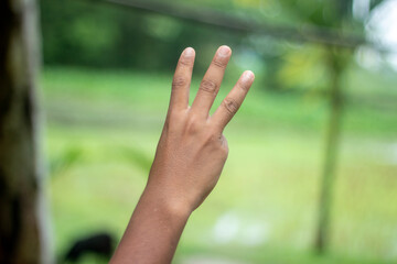 A man shows his hand with three fingers and the background blur