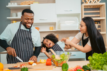 Kind African american parents teaching their adorable daughter how to cook healthy food, free space of kitchen, Happy black people family preparing healthy food in kitchen together