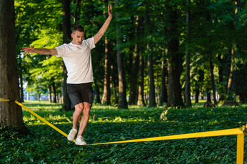 Young guy in sportwear walking on the rope and looking focused