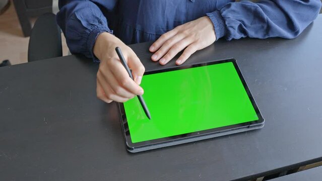 Young female hands sketching on tablet with digital pencil, at wooden desk