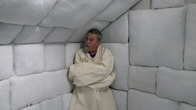Crazy man in straight jacket in an asylum mental hospital padded cell.