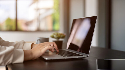 Close-up rear view image of a businesswoman working on her laptop computer at her desk in the office