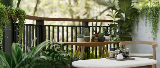 Copy space on a coffee table on a greenery apartment balcony with various tropical plants.