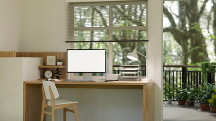 A minimalist and comfortable home workspace interior design with a computer mockup on a wooden table