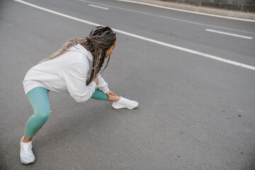 African fitness woman doing stretching exercises outdoors