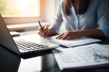 Closeup shot of businesswoman using a calculator and laptop in an office.