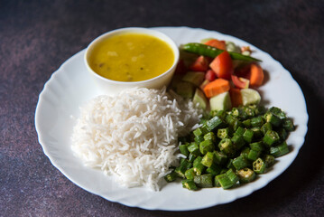 Healthy Indian veg meal rice, dal, vegetables and salad served in a plate. Close up, selective focus.
