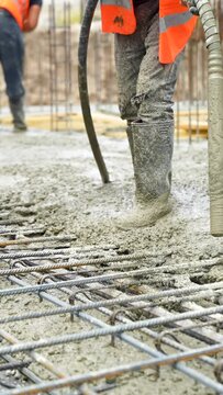Iron grate or reinforcement on the ground poured with concrete from a pipe at a construction site