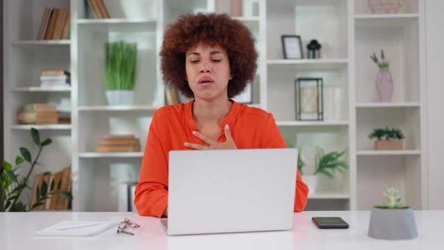 Multicultural young woman with curly hairstyle suffering from severe chest pain during panic attack at workplace. Company female worker having breathing problems during uncontrollable stress.
