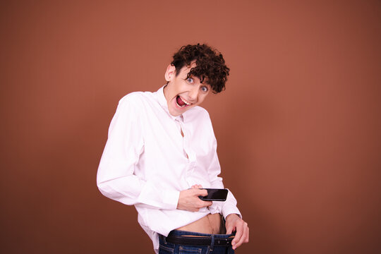 Funny young man posing on a brown background and being photographed.