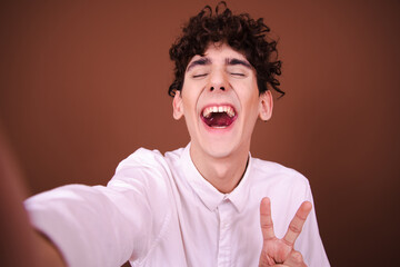 Funny young man posing on a brown background and being photographed.
