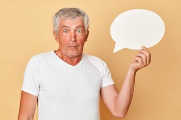 Frame for your words or symbols. Leave your mark. An empty template for your messages. Surprised amazed astonished gray haired mature man pensioner wearing white T-shirt isolated over beige background