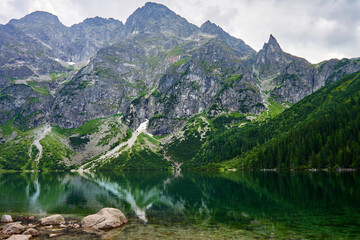 Naklejka na ściany i meble Amazing view on mountains range near beautiful lake at summer day. Tatra National Park in Poland. Panoramic view on Morskie Oko or Sea Eye lake in Five lakes valley