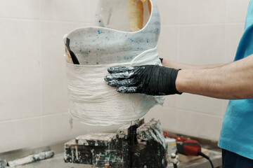 Closeup of crop unrecognizable male worker in black rubber gloves making hip disarticulation prosthesis mold with wet plaster in professional workshop