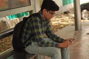 Young Indian middle class man sitting on bus stand