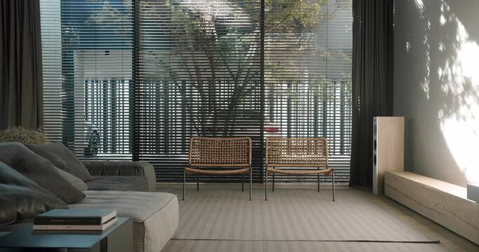 living room with panoramic window with blinds, comfortable couch, rattan armchairs and rug on floor in apartment with modern interior. contemporary design in cottage house.