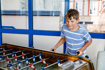 Smiling school boy playing table soccer. Happy excited child having fun with family game with...