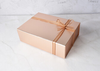 beautiful festive Christmas birthday premium luxury gift box packaging in shining bronze color and ribbon on white marble table different angle top view design photo shoot