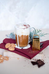 Still life with a cup of coffee latte, cookies and cade branch in Christmas mood. Small gold grater for chocolate. Copy Space