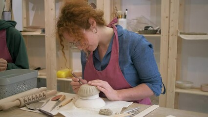 Woman working in pottery studio workshop making bowl from clay.