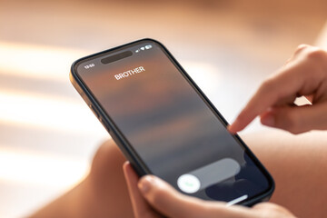 Smartphone in child hands with Incoming brother call on a screen.
