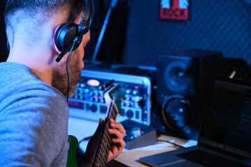 Musician man playing electric guitar with headphones at home recording studio. Music production.