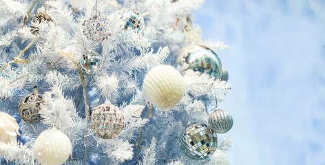Close up of Christmas tree with white ornaments.