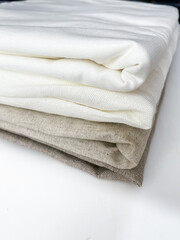 A stack of natural cotton and linen fabrics on a white background.