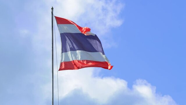 Waving Kingdom of Thailand flag on a pole with blue sky and white clouds on background, high quality 4K slowmotion thai patriotic concept footage. Bangkok, Thailand.