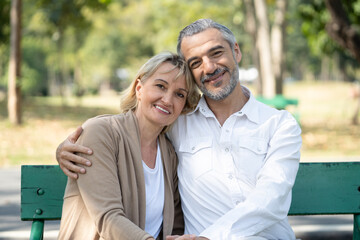 Elderly couple lifestyle concept. Husband embrace wife and sit on seat in the park relax on retirement life.