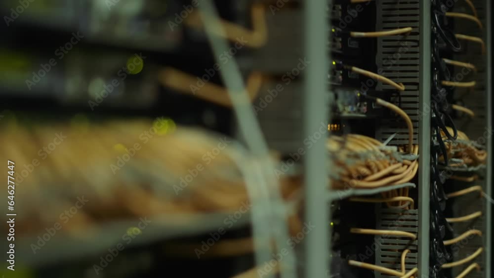 Poster pan to left of computer server deck rack cables and blinking lights in data centre