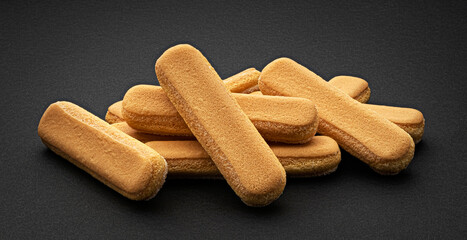Italian biscuits on black background, ladyfinger cookies, full depth of field