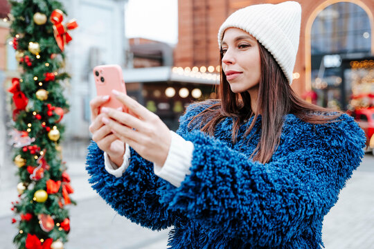 Woman wearing knit hat taking selfie at Christmas market