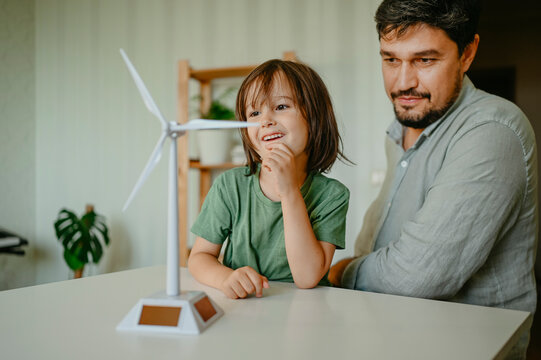 Father and son examining wind turbine model at home