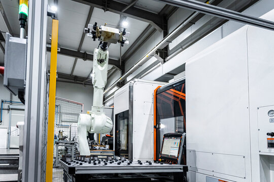 White robotic arm with cnc automated machinery in factory
