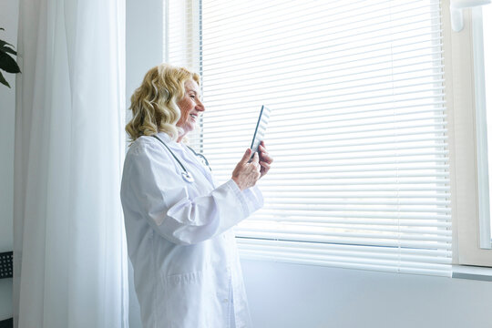 Smiling senior doctor consulting on video call through tablet PC