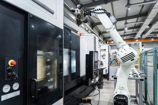 White robotic arm with cnc machinery in factory - Powered by Adobe