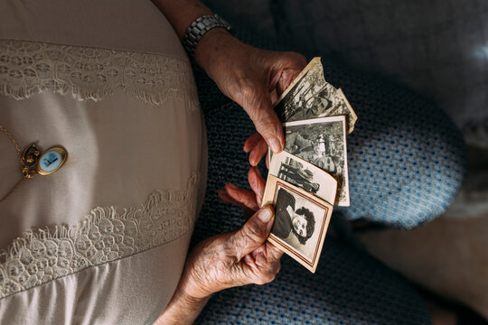Senior woman holding photographs from past at home