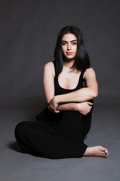 Beautiful young woman sitting against black background
