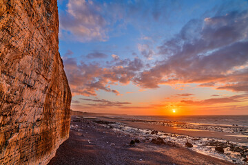 Chalk cliffs near coastline at sunset under cloudy sky